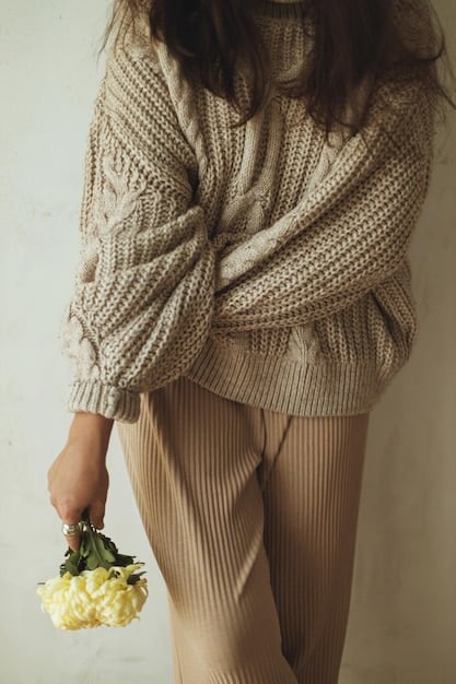 A woman wearing a capsule wardrobe outfit consisting of a neutral-colored knit sweater, black trousers, and a pair of minimalist sneakers. The image captures the simplicity and elegance of a sustainable and versatile wardrobe.