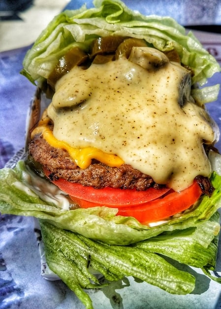 A close-up shot of a vibrant vegan burger made with a plant-based patty, stacked with fresh lettuce, tomato, avocado, and sprouts, showcasing the delicious and nutritious possibilities of plant-based cuisine.