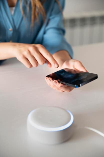 A close-up of a smart plug connected to a device, with a smartphone displaying an app that shows real-time energy consumption data for that particular device. Graphs and numeric values are visible on the app screen.