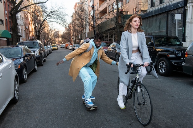 A bustling city street scene with various modes of sustainable transportation in motion. A cyclist rides in a designated bike lane, an electric bus is picking up passengers, and pedestrians are walking along tree-lined sidewalks. Solar panels are visible on the rooftops of nearby buildings, emphasizing the city's commitment to sustainability.