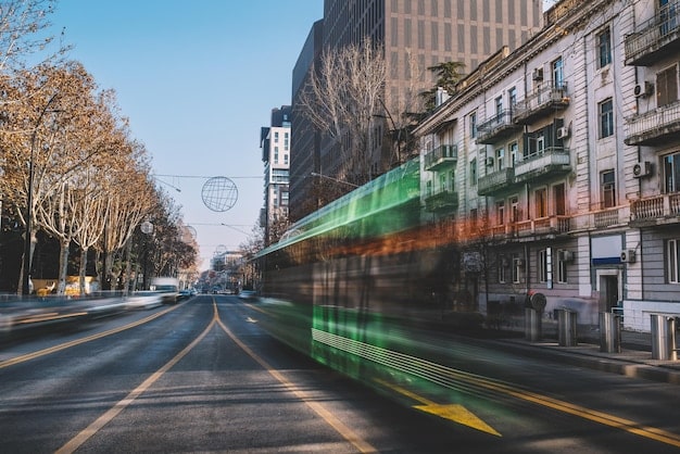 A modern electric bus driving through a busy downtown area, highlighting the city's commitment to sustainable transportation and reducing carbon emissions.