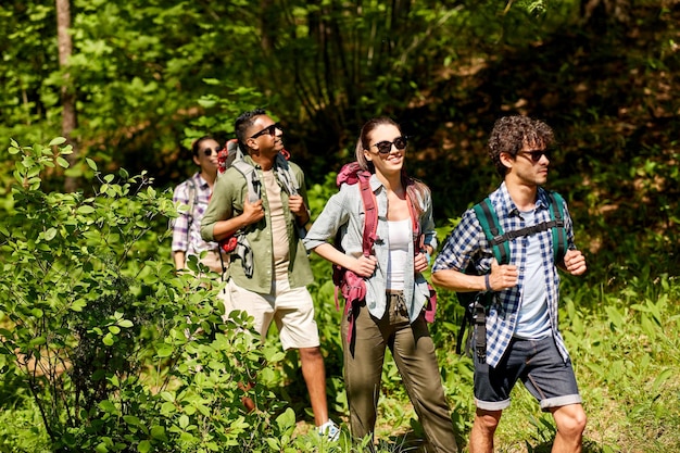 A group of tourists wearing colorful outdoor gear hiking through a dense, green forest, focusing on their expressions of enjoyment and connection with nature. Sunlight filters through the canopy, creating a dynamic and inviting atmosphere.