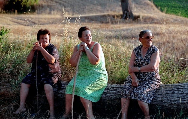 A group of indigenous elders standing in front of a deforested area, their faces showing concern and sadness.