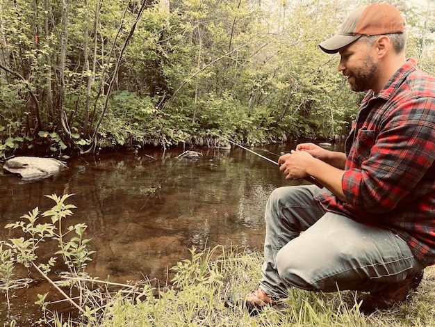 A close-up shot of a person fishing in a pristine river, surrounded by a lush forest. The image illustrates the direct economic impact of wildlife recreation on local communities.